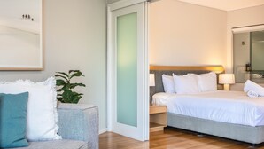 Una habitación de hotel con una cama, un sofá, una mesa de centro de vidrio y un ventanal grande.