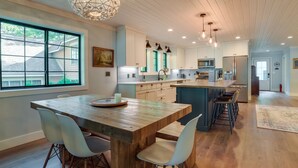 Een moderne keuken met een houten kookeiland, witte kastjes en hanglampen.