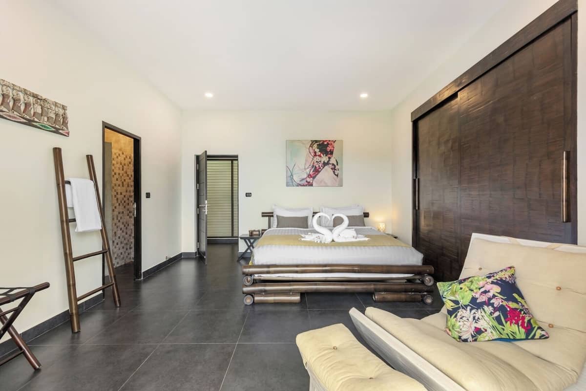 Quarto de hotel moderno com uma cama grande, um sofá, uma escada e um quadro na parede.