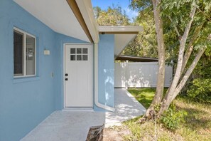 A house with a blue exterior, a white door, and a small window. - Stunning Newly Renovated River District Residence (Fort Myers)