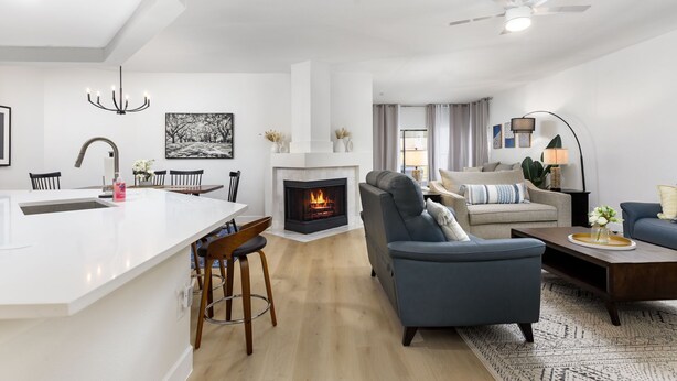 A modern living room with a fireplace, a dining area with a white island, and a seating area with a blue sofa and a coffee table. - Modern Retreat Near Lackland AFB  Ideal for Longer Stays (San Antonio)