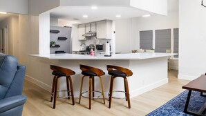 A modern kitchen with a central island, bar stools, and a blue rug. - Modern Retreat Near Lackland AFB  Ideal for Longer Stays (San Antonio)