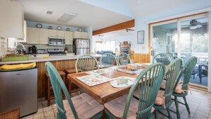 A kitchen with wooden cabinets, a refrigerator, and a dining area with a wooden table and chairs. - Private Pool, Spa & Spacious Deck (Corolla)