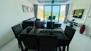 Un salon moderne comprenant un coin repas, de grandes fenêtres, un ventilateur de plafond et un téléviseur à écran plat.