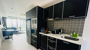 Une cuisine moderne avec des meubles de couleur noire, un évier en acier inoxydable et un four encastré.