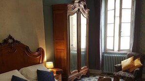 A bedroom with a large bed, a wooden wardrobe, a mirror, a chair, and a window with curtains. - La Scierie  (Quillan)