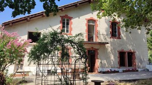 A two-story building with a balcony, a window with a red frame, and a door. - La Scierie  (Quillan)