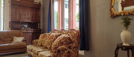 Un salón tradicional con un sofá estampado, un aparador de madera y un espejo grande.