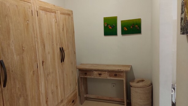 Une petite pièce, de taille modeste, comprenant une armoire en bois, un bureau et deux œuvres d’art murales vertes.