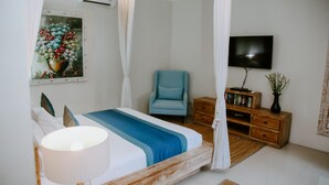 A bedroom with a bed, a chair, a TV, a wooden nightstand, and a wall-mounted painting. - Villa Martini in heart of Seminyak (Seminyak)
