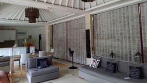 A modern living room with a grey sofa, a coffee table, and a dining area with a table and chairs. - Villa Martini in heart of Seminyak (Seminyak)