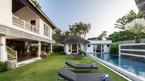 A modern house with a swimming pool, two lounge chairs, and a well-maintained lawn. - Kerta Rama Seminyak (Keroboken Kelod)
