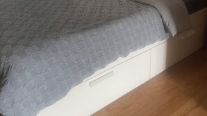 A bedroom with a bed, a brick wall, and a window with blinds.