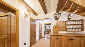 A hallway with wooden doors and a tiled floor leading to a dining area.