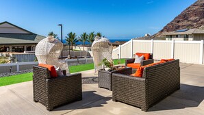 An outdoor patio area with wicker furniture, decorative planters, and a view of the ocean.