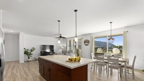 A modern kitchen with a large island, wooden cabinets, and a dining area with a table and chairs.