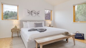 A neatly arranged bedroom with a large bed, bedside tables, a bench, and artwork on the wall. - Red Rocks Views, Walk to Jordan Trailhead, Hot Tub | Sedona Sunrise by AvantStay (Sedona)
