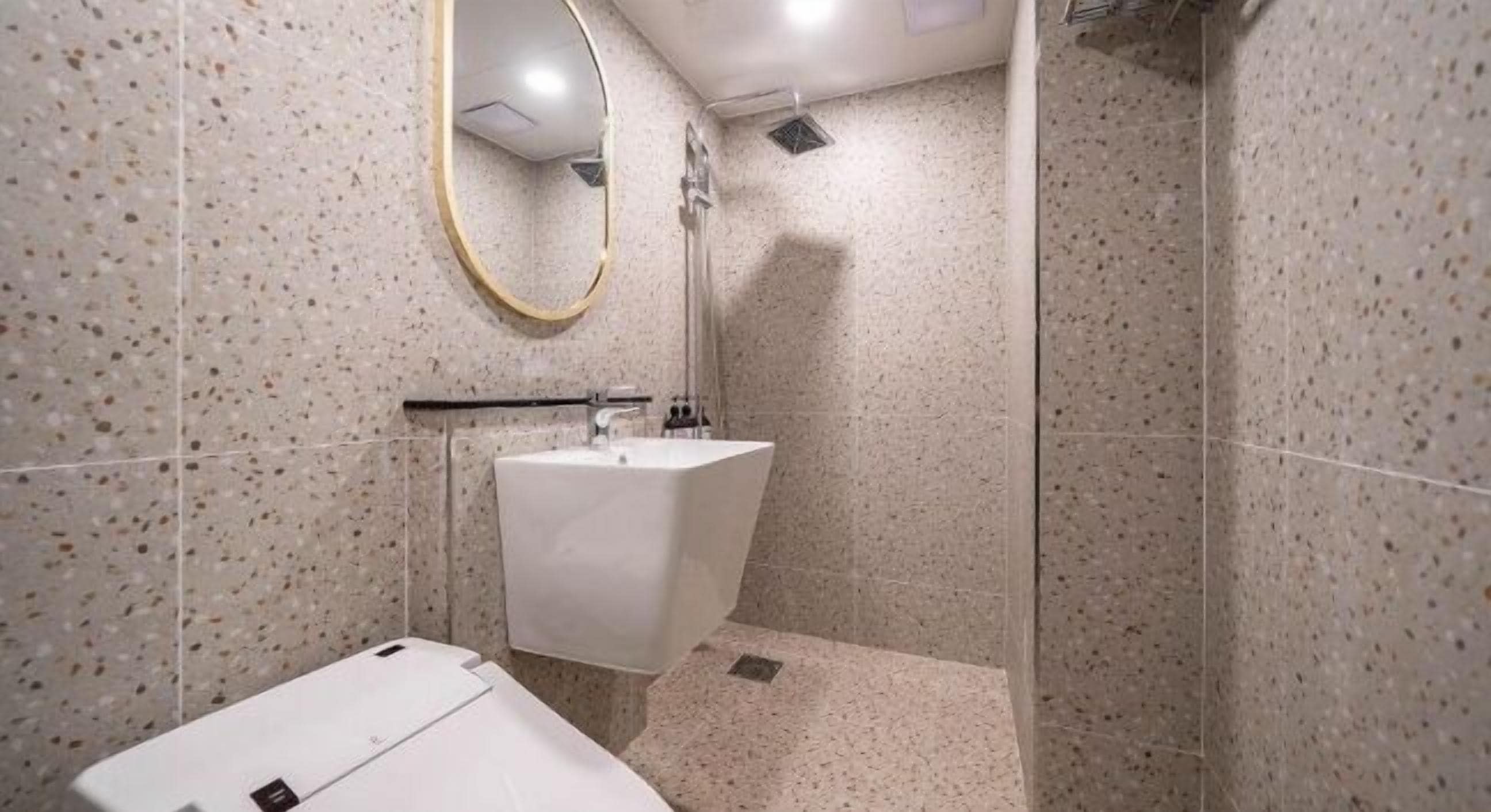 Un baño moderno con un lavamanos independiente, un espejo y una zona de ducha.