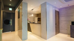 A modern reception area with marble walls, a reception desk, and a wooden panel wall. - Hotel Gate (Incheon)