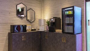 A modern bathroom with a dark wood vanity, a coffee machine, a refrigerator stocked with beverages, and a mirror on the wall. - Hotel Gate (Incheon)