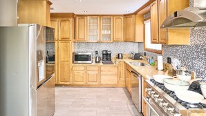 A modern kitchen with wooden cabinets, stainless steel appliances, and a tiled backsplash. - Modern Retreat w/ Private Spa, Arcade, Playground, Disney, Convention & Beaches (Anaheim)