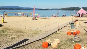 Una playa con una red de voleibol, sillas de playa y una carpa.