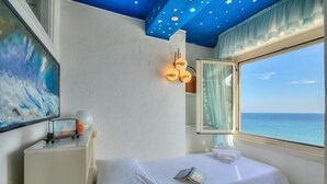 A bedroom with a bed, a nightstand, a painting, a window with a view of the sea, and a ceiling with star decorations. - Il Bijou Di Rossella - Beach Front Duplex With Balcony (Alassio)