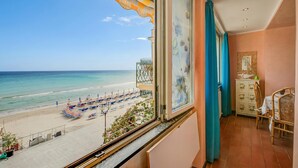 A balcony with a view of a beach, a dining area with chairs and a table, and a cabinet with decorative items. - Il Bijou Di Rossella - Beach Front Duplex With Balcony (Alassio)