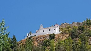 Un edificio bianco con tetto rosso situato su una collina, circondato dal verde.