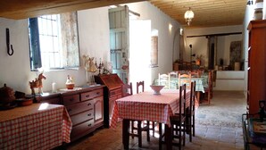 Un'area pranzo rustica con tavoli e sedie in legno, un'ampia finestra vista e un lampadario.
