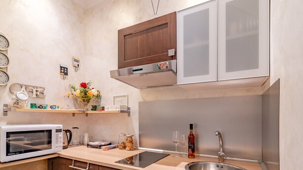 Eine moderne Küche mit Holzausstattung, einer Edelstahlspüle, einer Mikrowelle und einem Einbauofen.