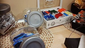 Ein Schreibtisch mit einem gerahmten Zertifikat, einer Briefumschlägen-Box und Glasbehältern mit Pasta.