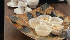 Eine Kaffeestation mit Kaffeemaschine, Tassen und einem Teller mit Keksen.