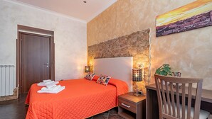 Ein Schlafzimmer mit einem großen Bett, einem Nachttisch, einem Sessel und einem Bild an der Wand.