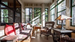 Una habitación acogedora con sofá, sillas, una mesita y ventanas amplias.