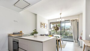 A modern kitchen with a central island, a built-in oven, and a dining area with a table and chairs. - Galatea | Beachfront - pool - gym (Torremolinos)