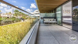 A modern balcony with a glass railing, a sofa, and a small table. - Galatea | Beachfront - pool - gym (Torremolinos)