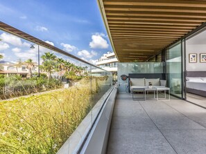 A modern balcony with a glass railing, a sofa, and a small table. - Galatea | Beachfront - pool - gym (Torremolinos)