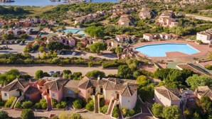A coastal residential area with houses, a swimming pool, and rocky terrain.