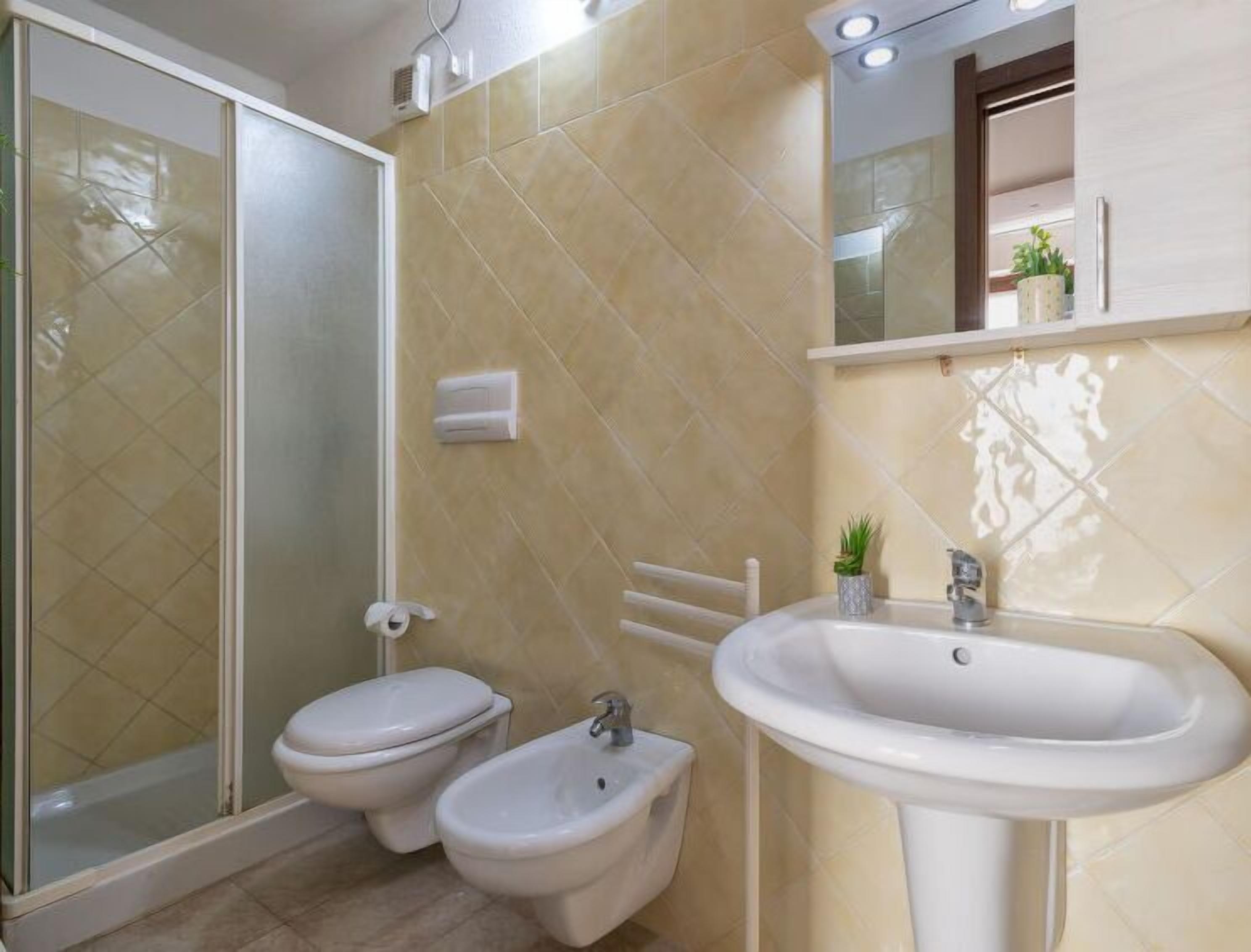 Une salle de bain avec douche, deux toilettes, un bidet et un lavabo.