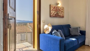 A room with a blue sofa, a hat, and a painting on the wall. - Vacation home Alice by Interhome (Badesi)