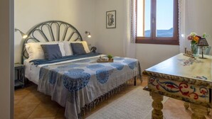 A bedroom with a bed, bedside table, lamp, and a window with curtains. - Vacation home Alice by Interhome (Badesi)