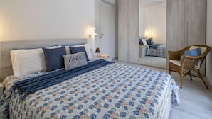A bedroom with a bed, a chair, a wardrobe, and a mirror. - Acqua Marina by Interhome (Valledoria)