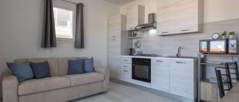 A modern kitchen with white cabinets, a built-in oven, and a microwave on a countertop.