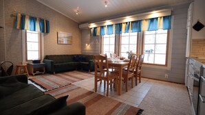 Un salon confortable avec un canapé d’angle, une table à manger avec des chaises et un coin cuisine équipé d’un réfrigérateur et d’une cuisinière.