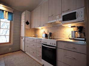A modern kitchen with white cabinets, a built-in oven, a microwave, and a coffee maker. - Tunturituuli a by Interhome (Inari)