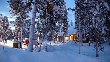 A snow-covered landscape with trees and a building in the background.