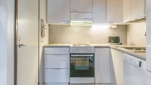 A compact kitchen with white cabinets, a stove, oven, and dishwasher. - Saarihely b 9 by Interhome (Inari)