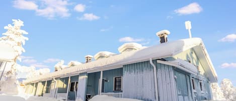 Una casa de madera cubierta de nieve con varias chimeneas y un porche.
