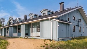 A row of blue wooden houses with a dirt path leading to the entrance. - Saarihely b 9 by Interhome (Inari)